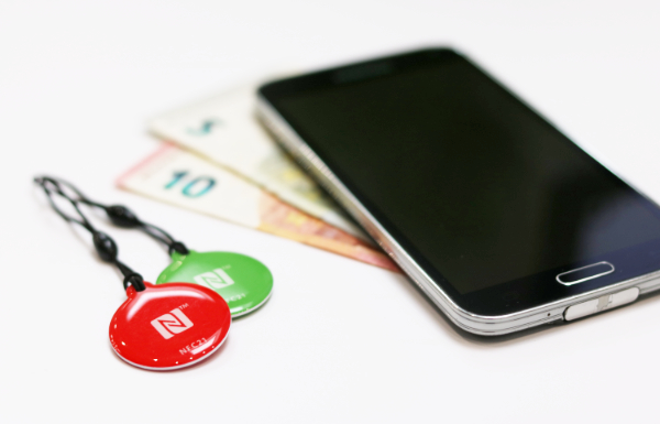 NFC-Smartphone, das auf Geldscheinen liegt. NFC-Schlüsselanhänger im Vordergrund