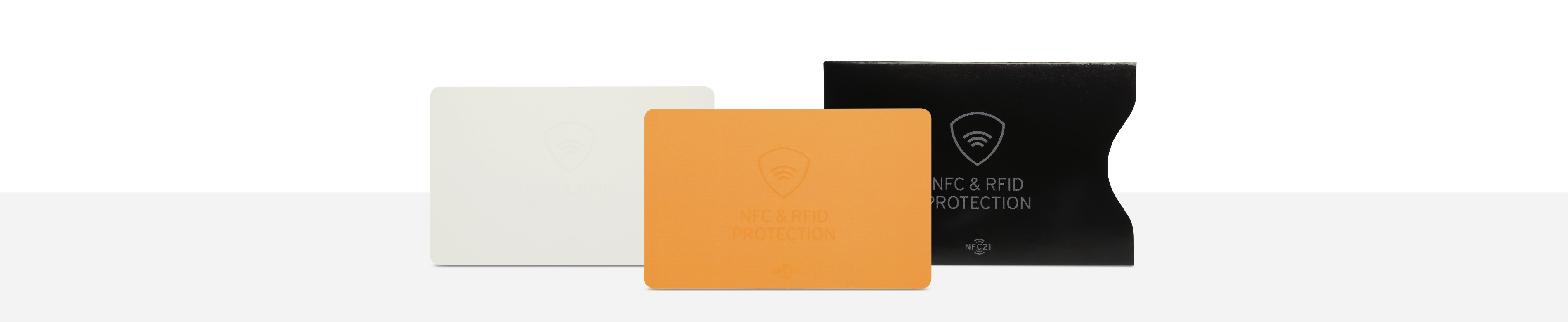 Zwei NFC Schutzkarten in Weiß und Orange  neben einer schwarzen NFC Schutzhülle