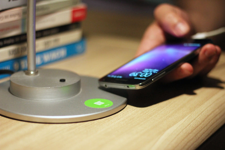 Jemand scannt einen NFC Sticker auf einer Nachttischlampe