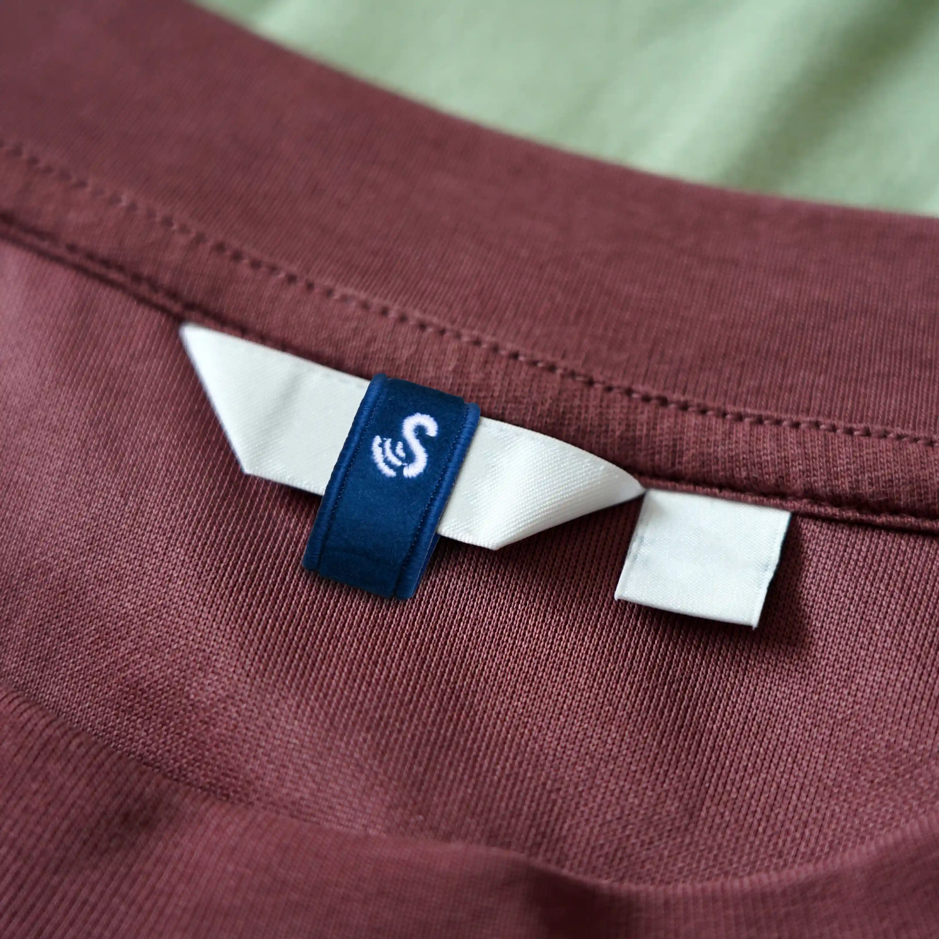 A dark blue SenseTap loop is wrapped around the brand label of a top. The embroidered SenseTap logo is clearly visible.